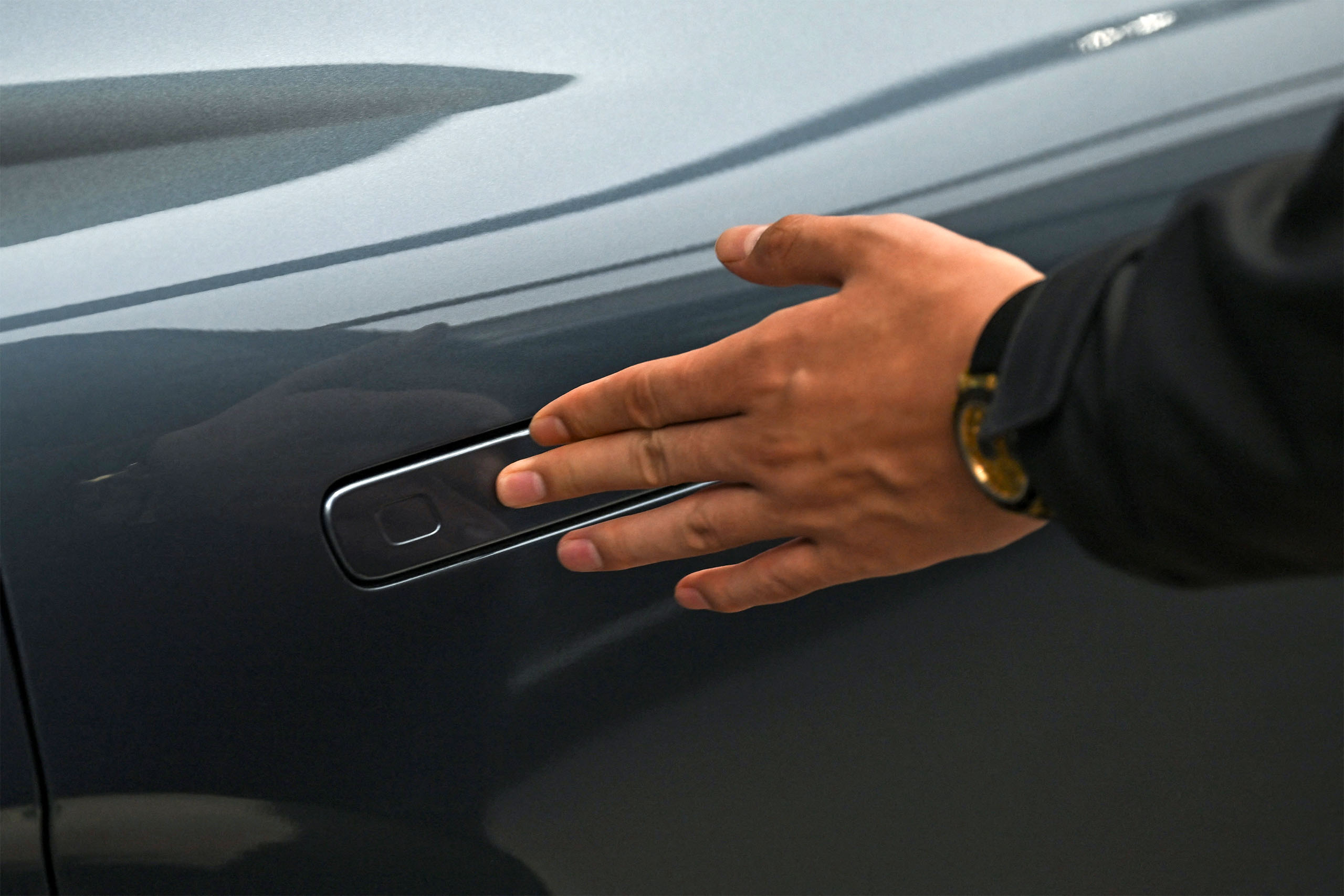 A man opens the door for a Zeekr X7 electric vehicle at a showroom in Beijing on February 3, 2026. China will ban hidden door handles on cars sold in the country from next year, phasing out the minimalist design popularised by Tesla over safety concerns. (Photo by Pedro Pardo / AFP via Getty Images)