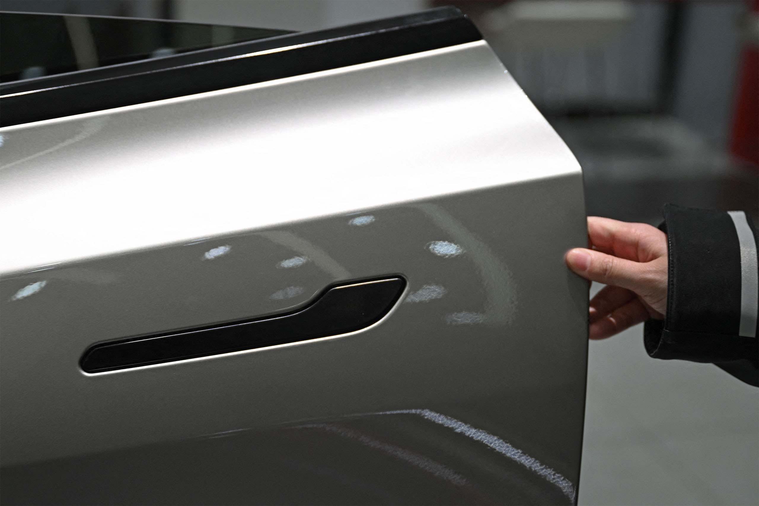 A woman opens the door for a Tesla Model YL electric vehicle at a showroom in Beijing on February 3, 2026. China will ban hidden door handles on cars sold in the country from next year, phasing out the minimalist design popularised by Tesla over safety concerns. (Photo by Pedro Pardo / AFP via Getty Images)